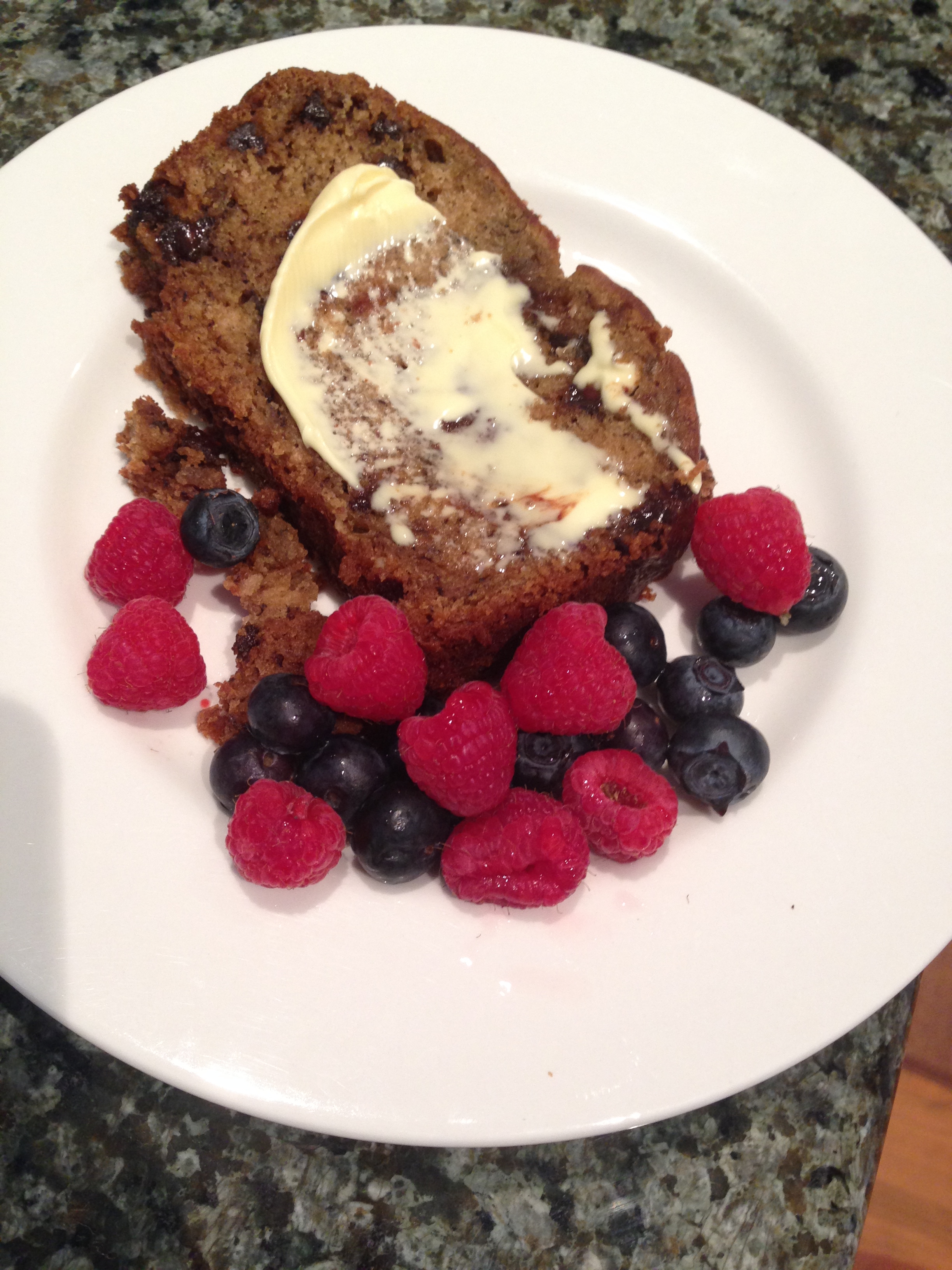 Banana chocolate chip bread with berries on white plate