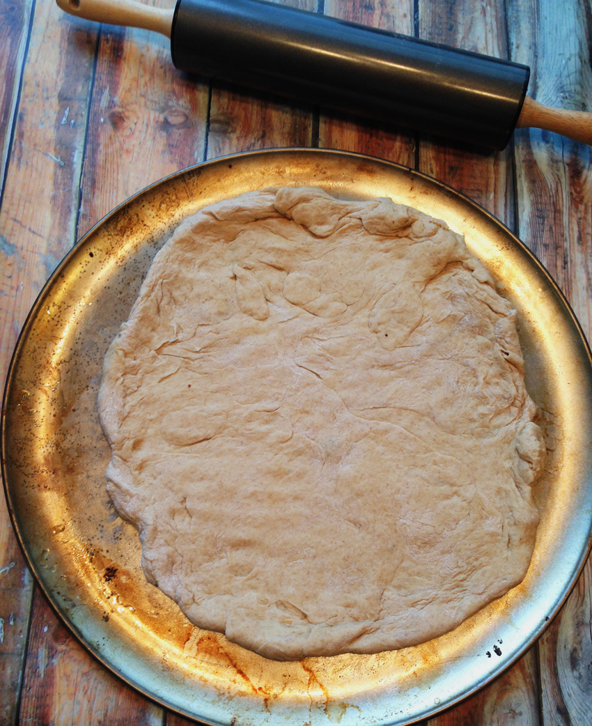 Whole wheat pizza dough spread out on pizza pan | Bucket List Tummy