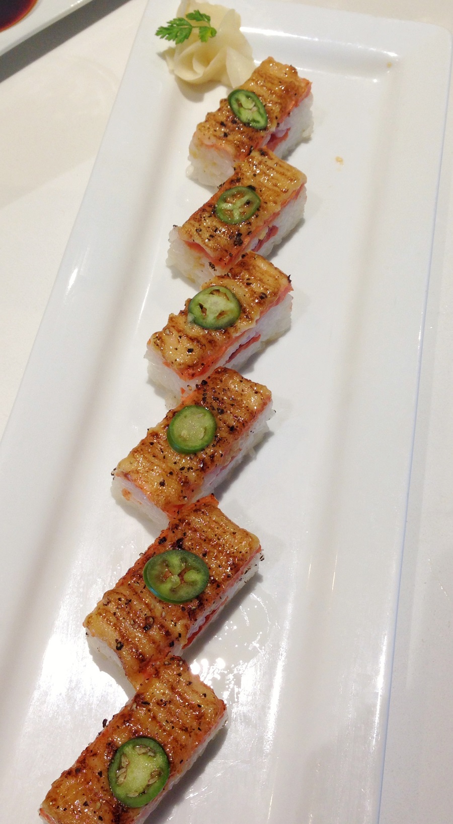 Sushi topped with jalapeno on white plate