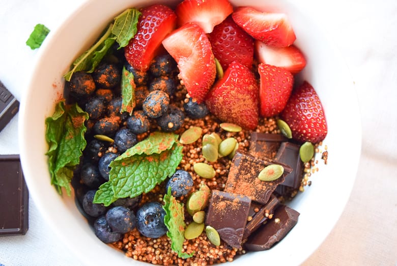 Quinoa breakfast bowl topped with pumpkin seeds and fruit
