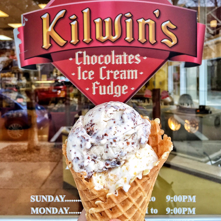 waffle cone with two scoops of ice cream in front of Kilwins window