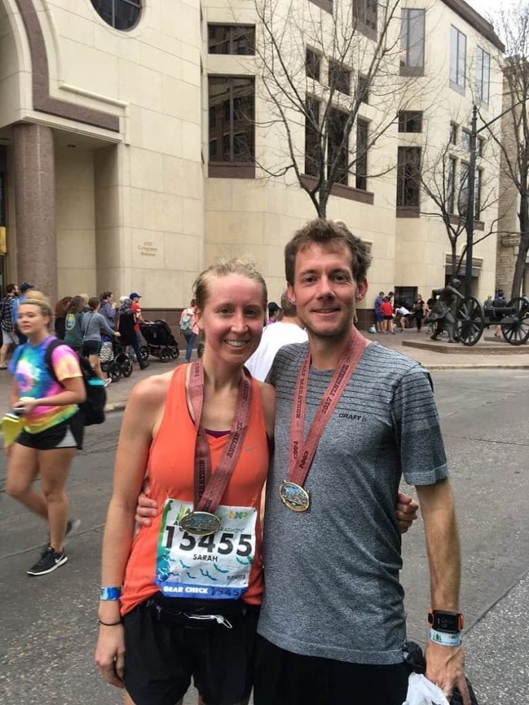 husband and wife wearing austin half marathon medals after running race 