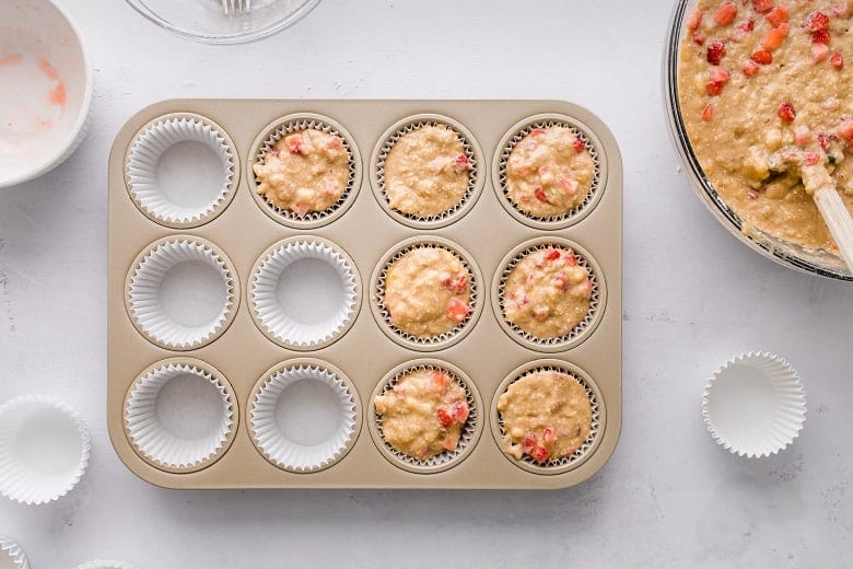 strawberry chickpea muffin batter in baking tin before baking with mixing bowl next to them