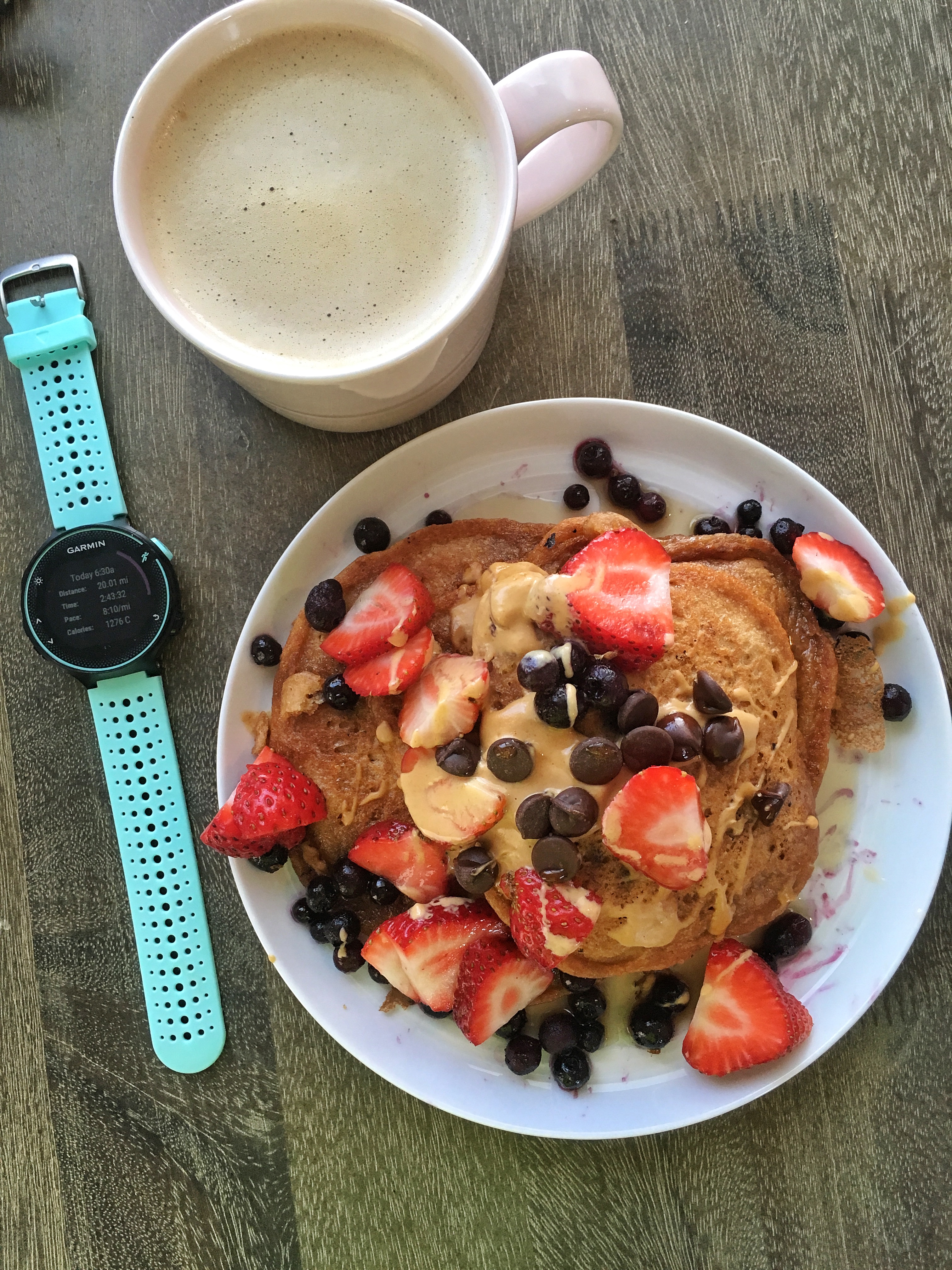 White plate with pancakes, peanut butter and fruit next to running watch 