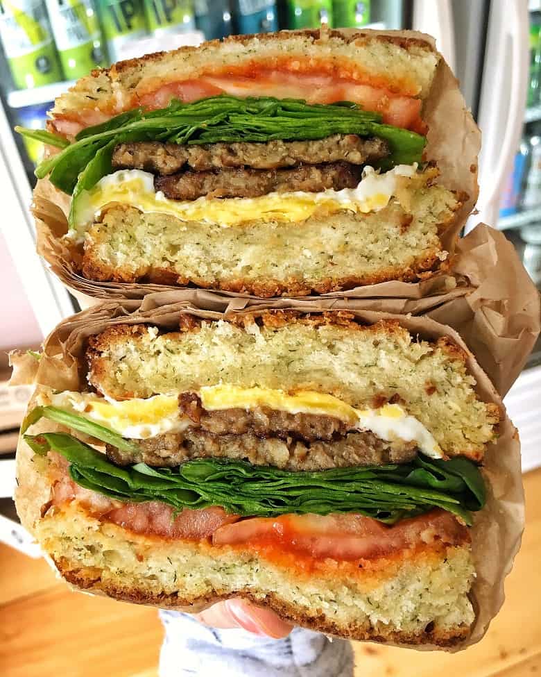 stacked breakfast sandwich with sausage, tomato, spinach and cream cheese