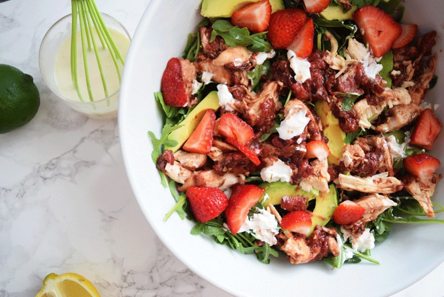 Chicken and strawberry salad served in white bowl topped with greek yogurt dressing