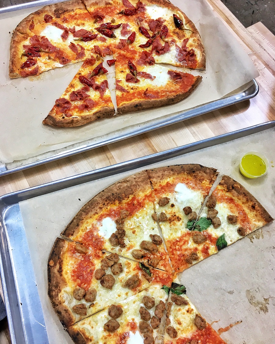 Two large pizzas to split on wooden table