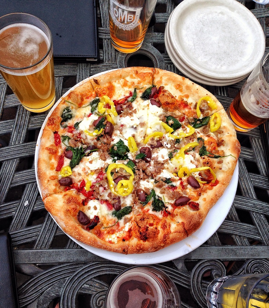 pizza with veggies and beers on outside patio
