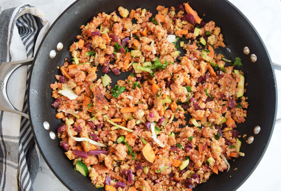 skillet with quinoa and vegetables for scramble next to striped napkin