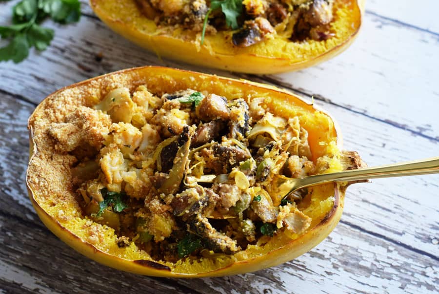 Vegetarian spaghetti squash casserole boats with fork on wooden table