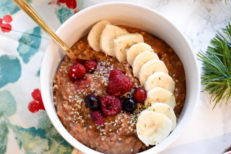 Gingerbread oatmeal in white bowl topped with berries and banana