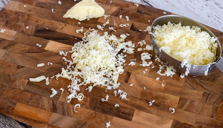 Cutting board with shredded cheddar cheese to make cheesy quinoa