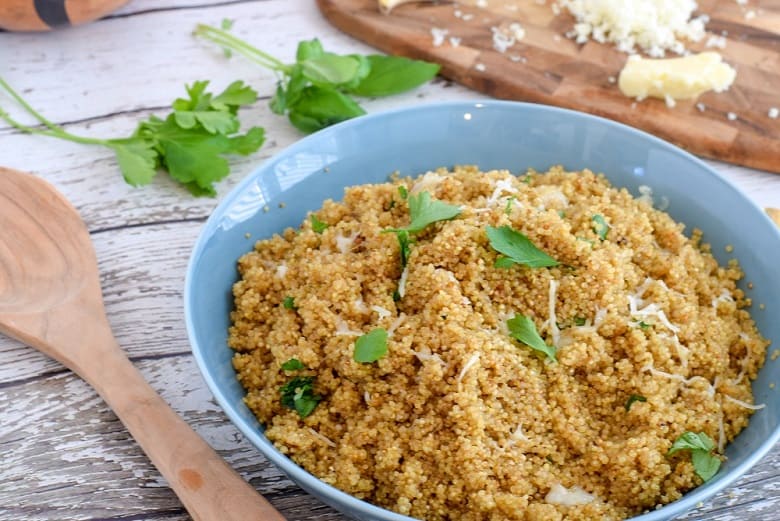 Garlic quinoa topped with cheese and herbs in blue plate