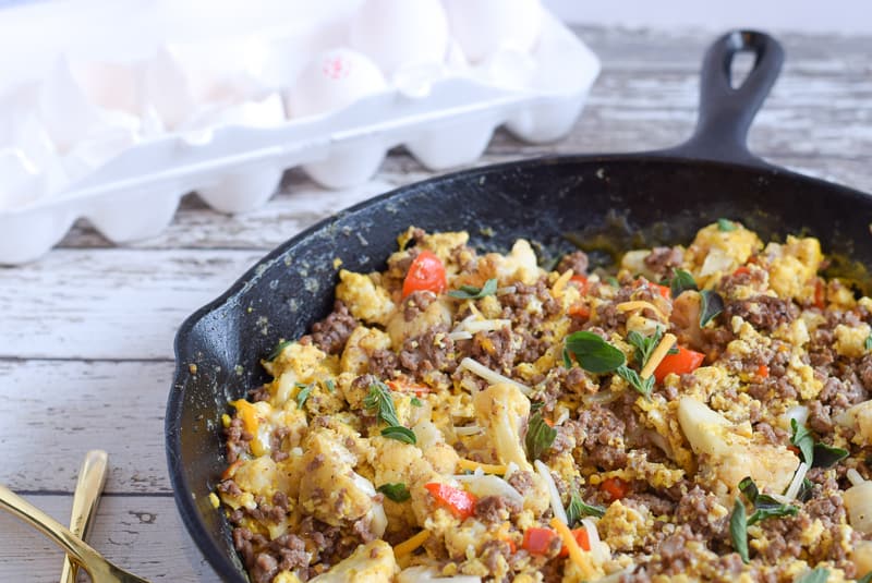 breakfast skillet with ground beef, cauliflower, eggs and cheese in cast iron pan