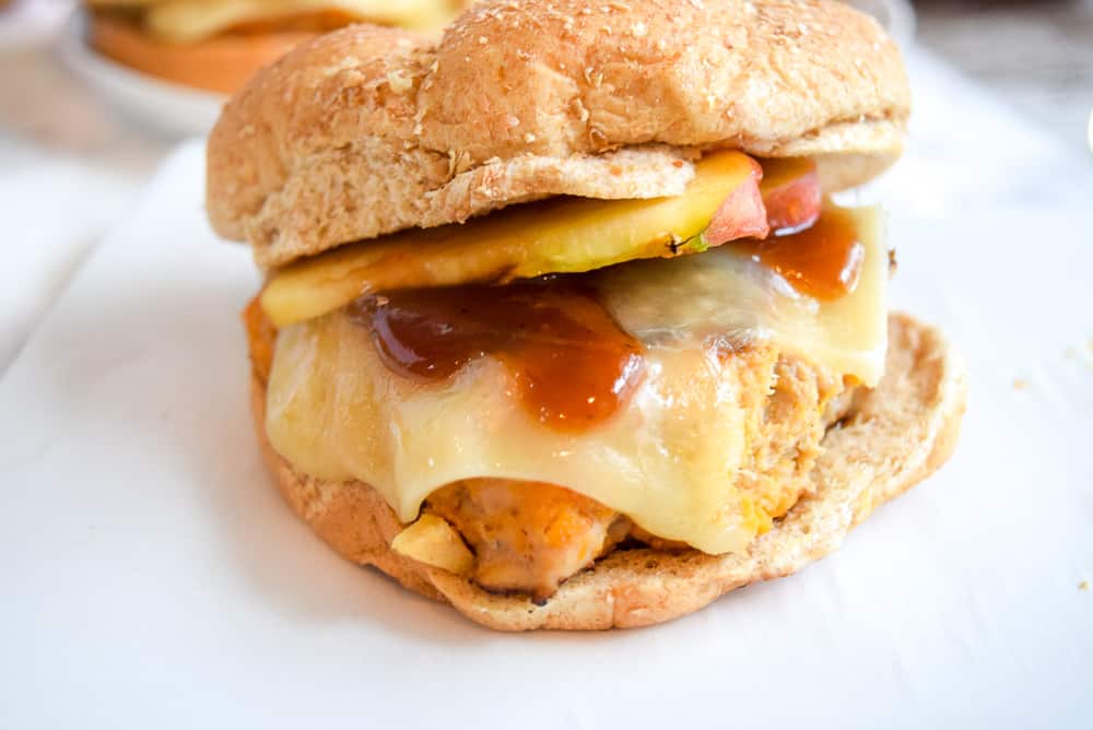 close up of apple turkey burger with melted cheese and apple on wheat bun