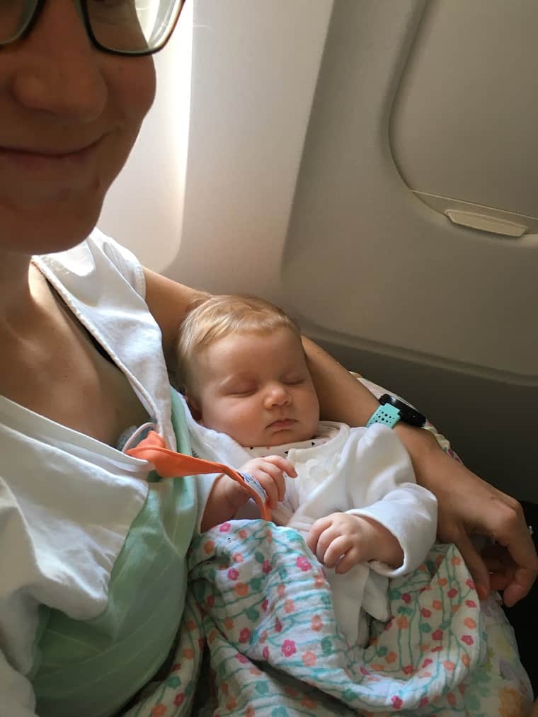 Baby sleeping in mom's arm on airplane