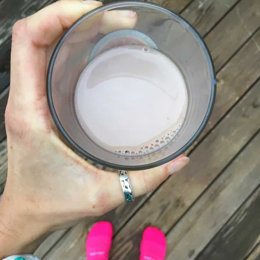 holding a glass of chocolate milk in clear glass