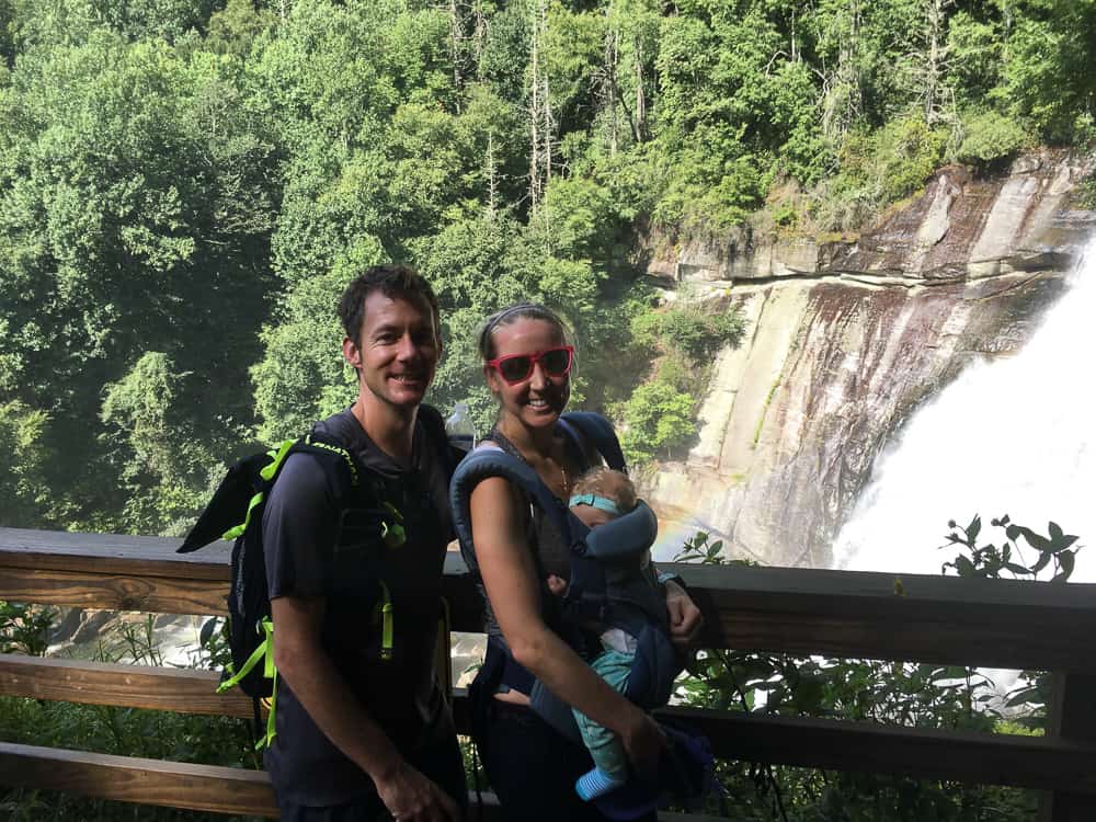 mom, dad and baby hiking in front of waterfall