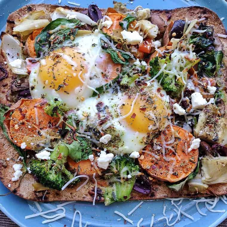 homemade pizza on blue plate with eggs, veggies and sweet potatoes