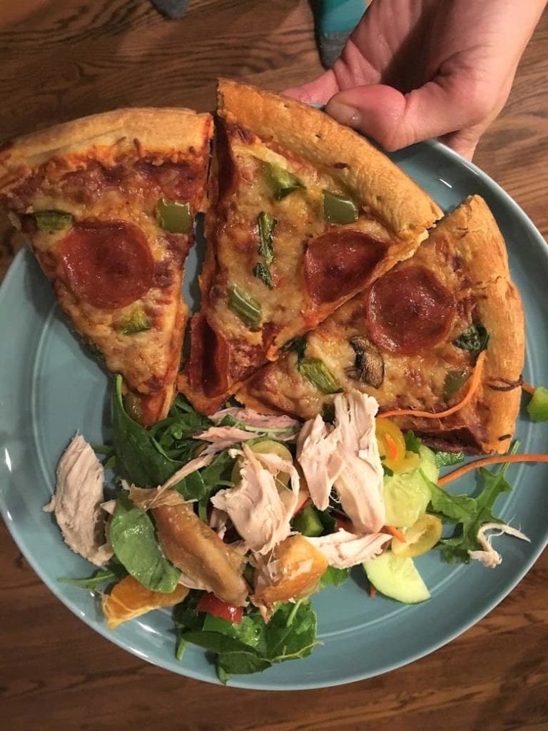 blue plate with slices of pizza on it and side salad with chicken
