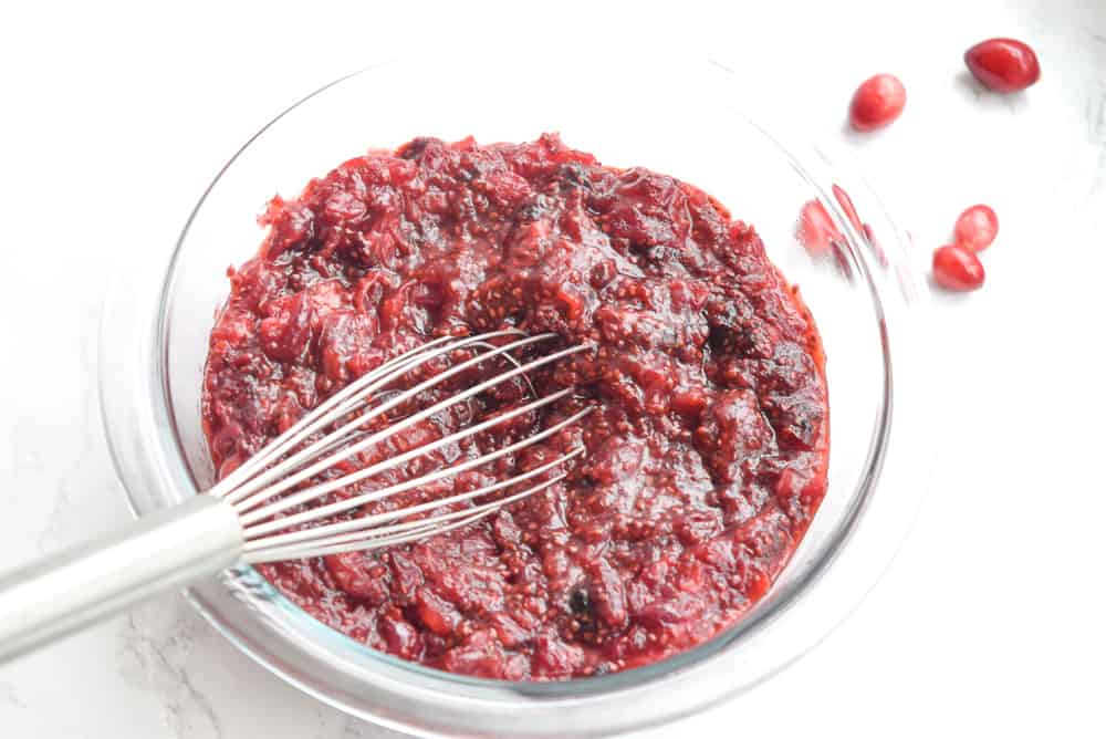 clear bowl with mashed strawberry chia jam and mixer