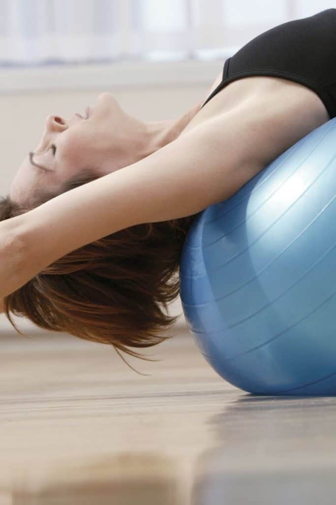 woman stretching over blue yoga bowl