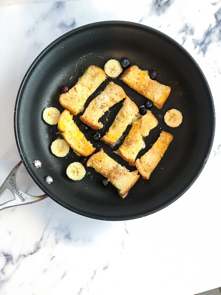 baby french toast cooking on skillet with sliced bananas