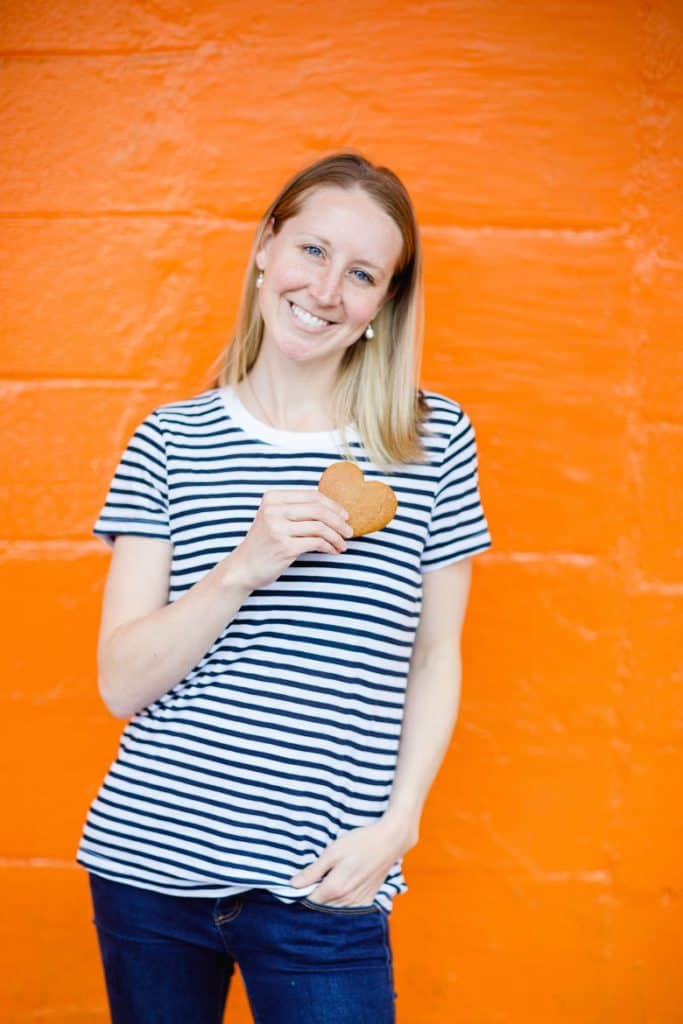 Girl holding cookie in front of orange wall | Bucket List Tummy