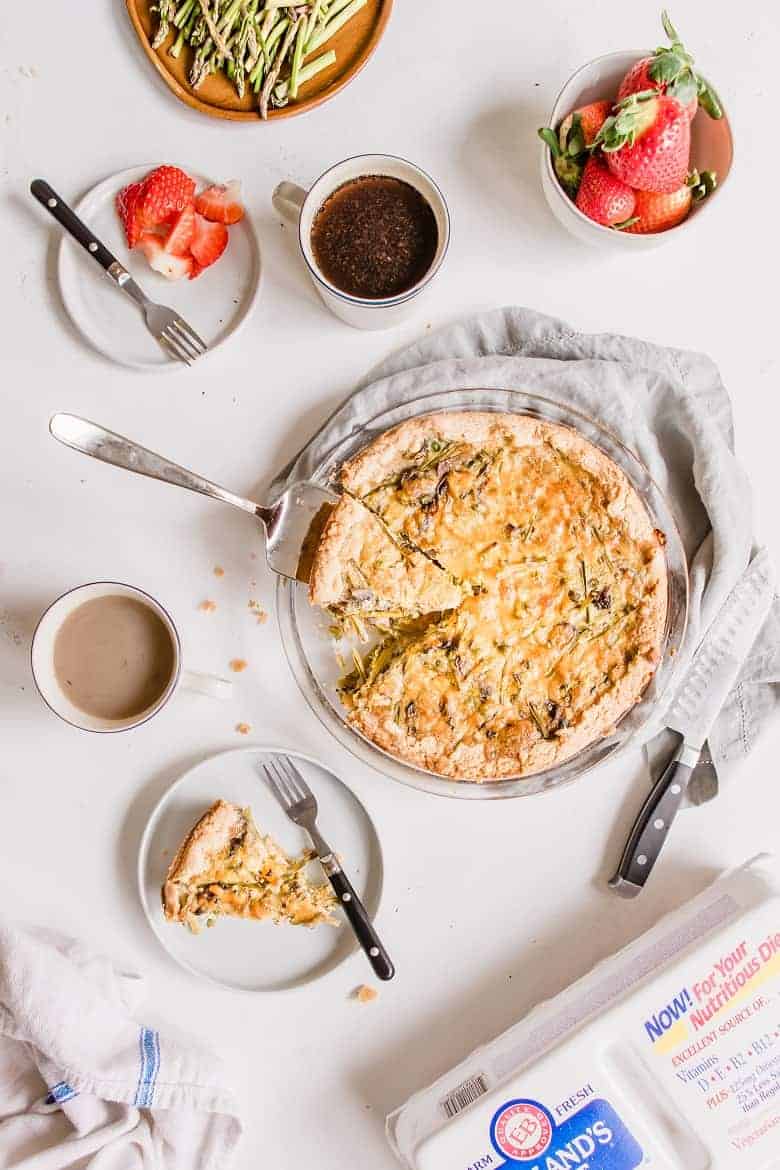 Pie serving of asparagus mushroom quiche with coffee and strawberries 