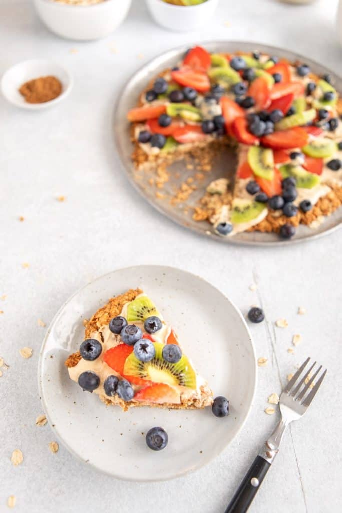 Slice of breakfast fruit pizza on white plate with fork | Bucket List Tummy