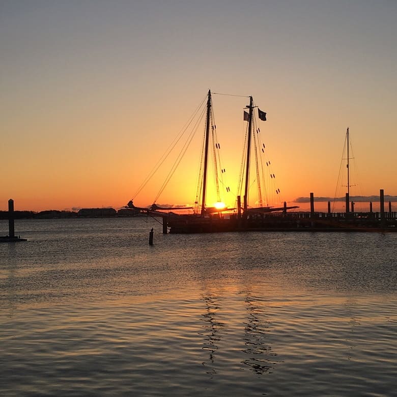 Charleston, SC sunset with a sailboat in front of it
