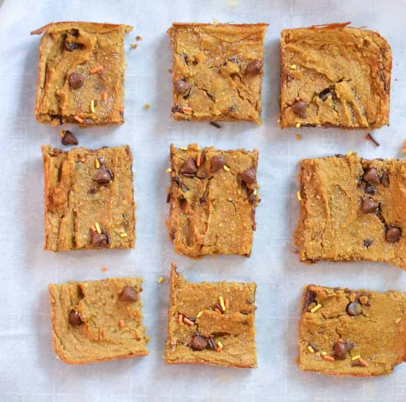 Freshly baked Vegan Pumpkin Blondies with chocolate chips cut into 9 squares on parchment paper