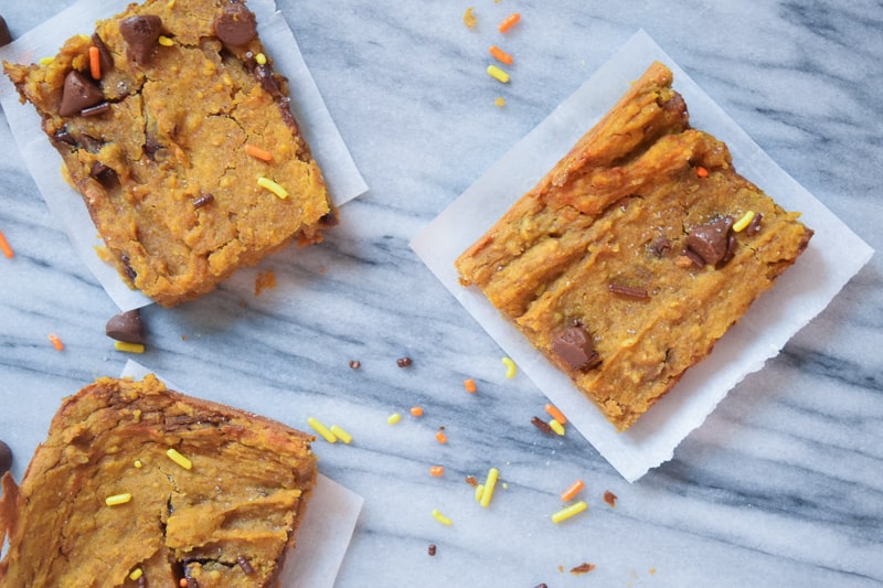 Overhead view of pumpkin blondies on parchment paper with sprinkles 