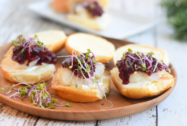 Alaska cod sliders with cranberry churney on brown serving board topped with sprouts