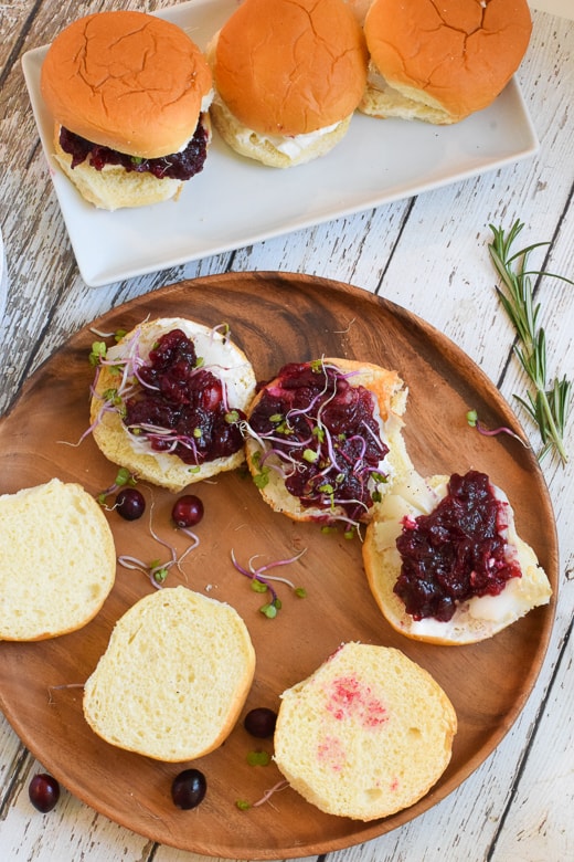 Open faced fish sliders topped with cranberry sauce on brown plate
