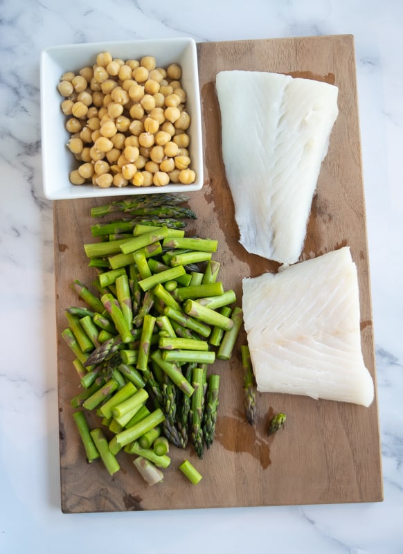 Alaskan halibut with chopped asparagus and chickpeas on cutting board