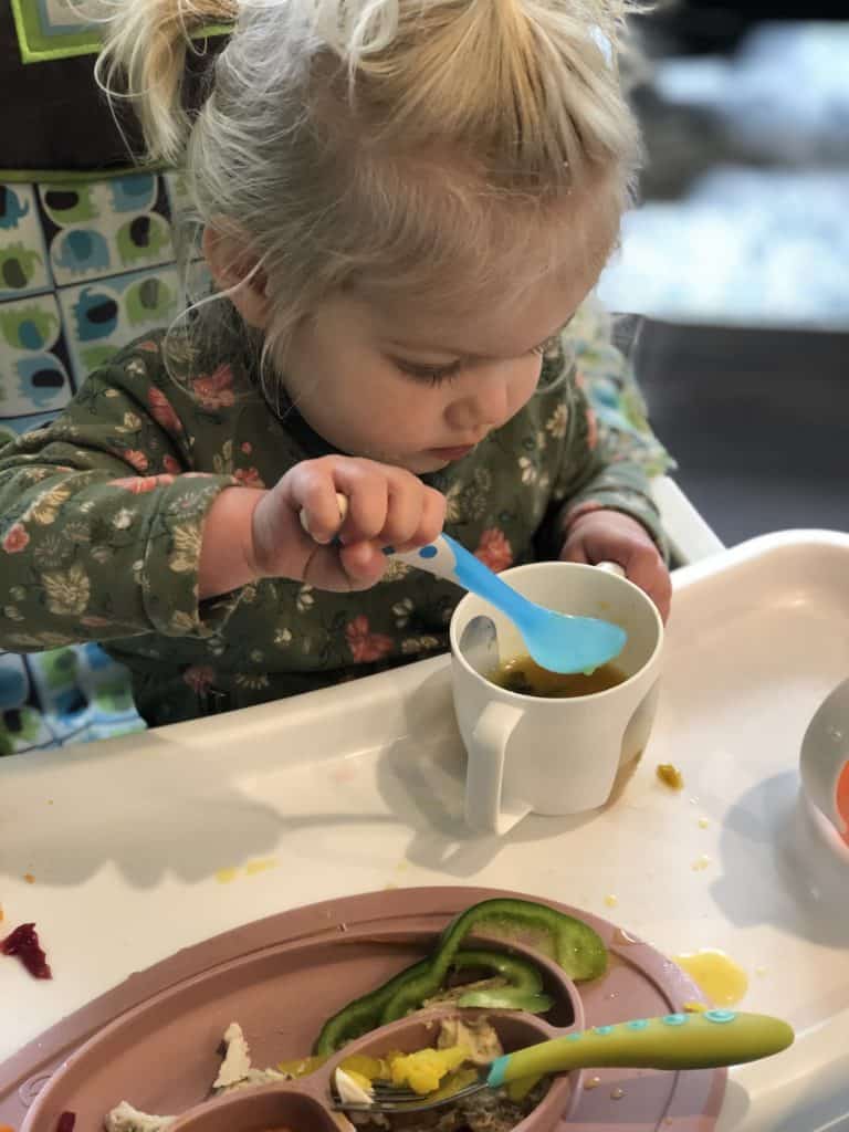 toddler tasting soup out of a cup