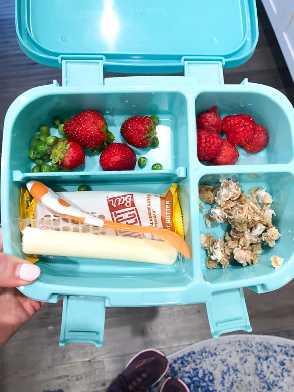 Bentgo lunch box with string cheese, perfect bar, strawberries, peas and raspberries
