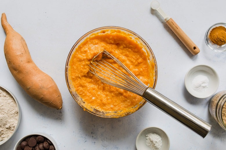 Mixing bowl of wet ingredients for sweet potato bread on gray background