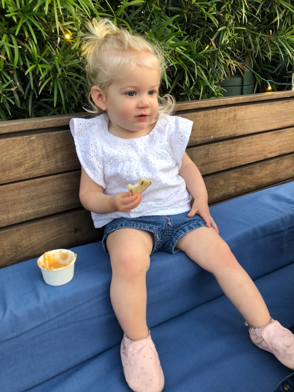 Toddler eating a snack on a bench