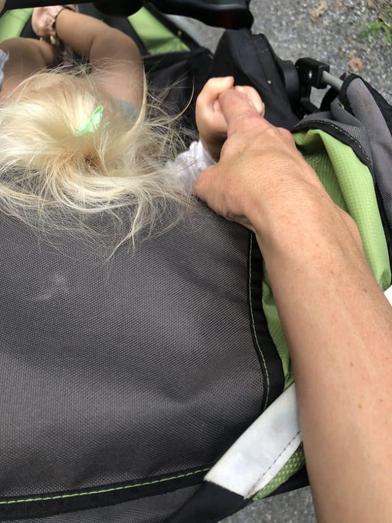 Toddler holding mom's finger in running stroller