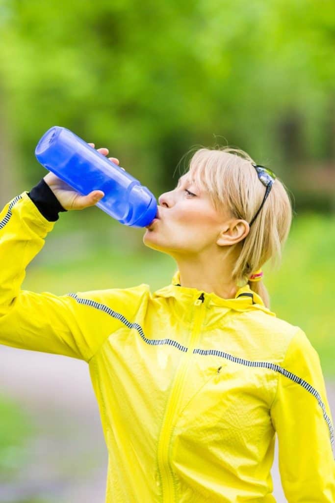 woman drinking water before running