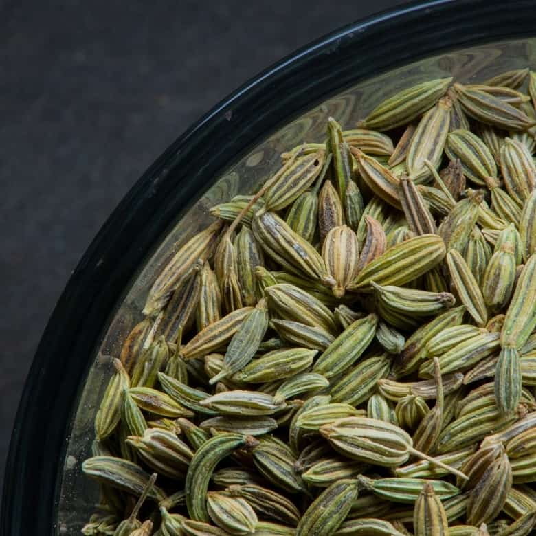 close up of fennel seeds in bowl over dark background
