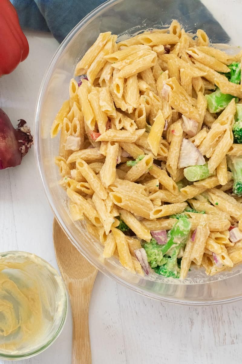gluten free pasta salad in clear bowl with vegetables and hummus pasta sauce dressing