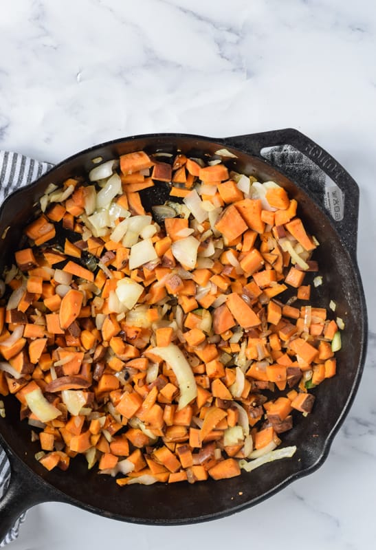 Sauteed onions and sweet potatoes in cast iron skillet 