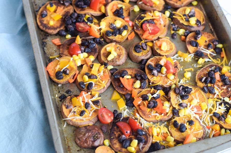 loaded sweet potato nachos on baking sheet with vegetarian toppings
