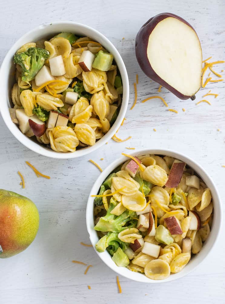 bowls of toddler mac and cheese with pears and broccoli in two white bowls on white counter