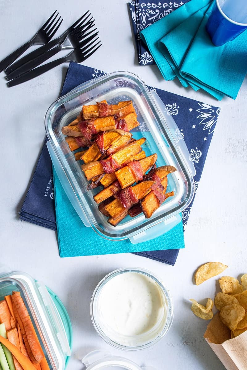 bacon wrapped sweet potato fries in clear tupperware on blue napkin 