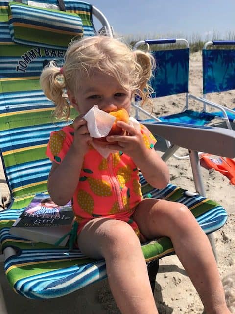 toddler eating peach on beach chair