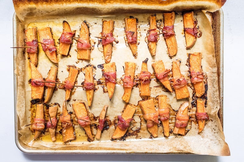 Sweet potatoes wrapped in bacon on baking sheet